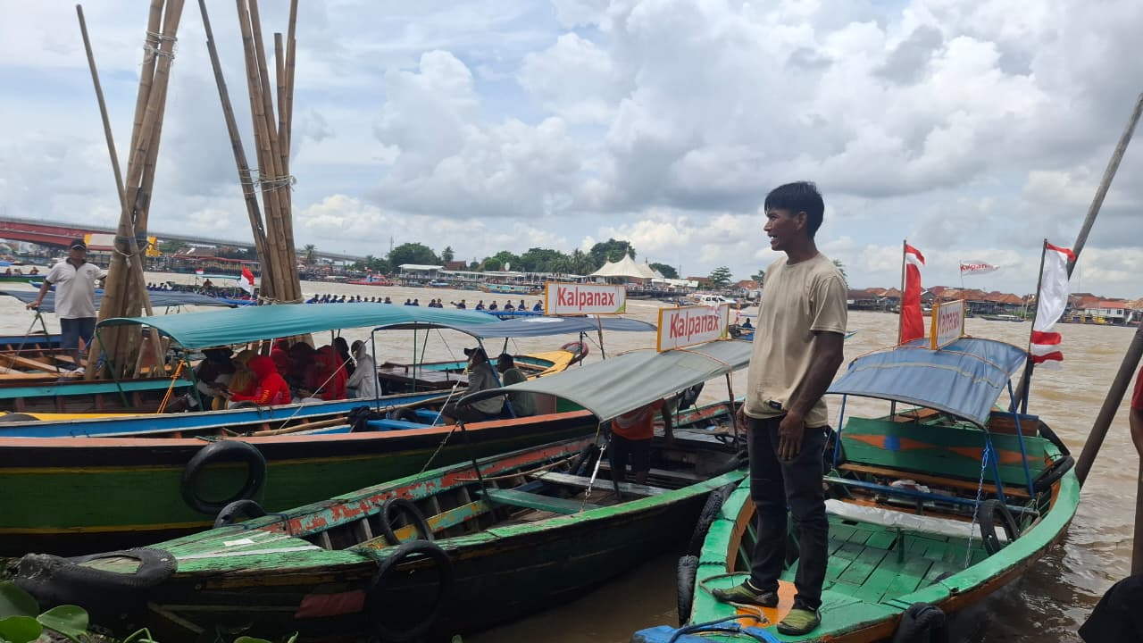 Hasad (37) menunggu penumpang yang ingin menaiki perahu ketek di sela-sela lomba Bidar di Sungai Musi, Kamis (17/8/2025) (Melati Arsika / Simburcahaya.com)